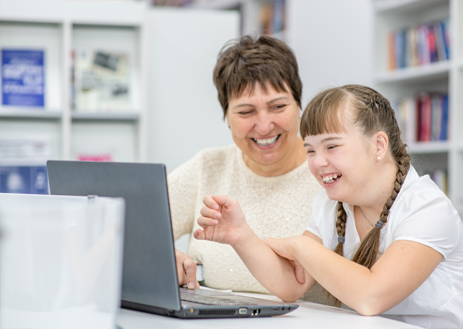 Image of a young girl learning along a teacher on a laptop.