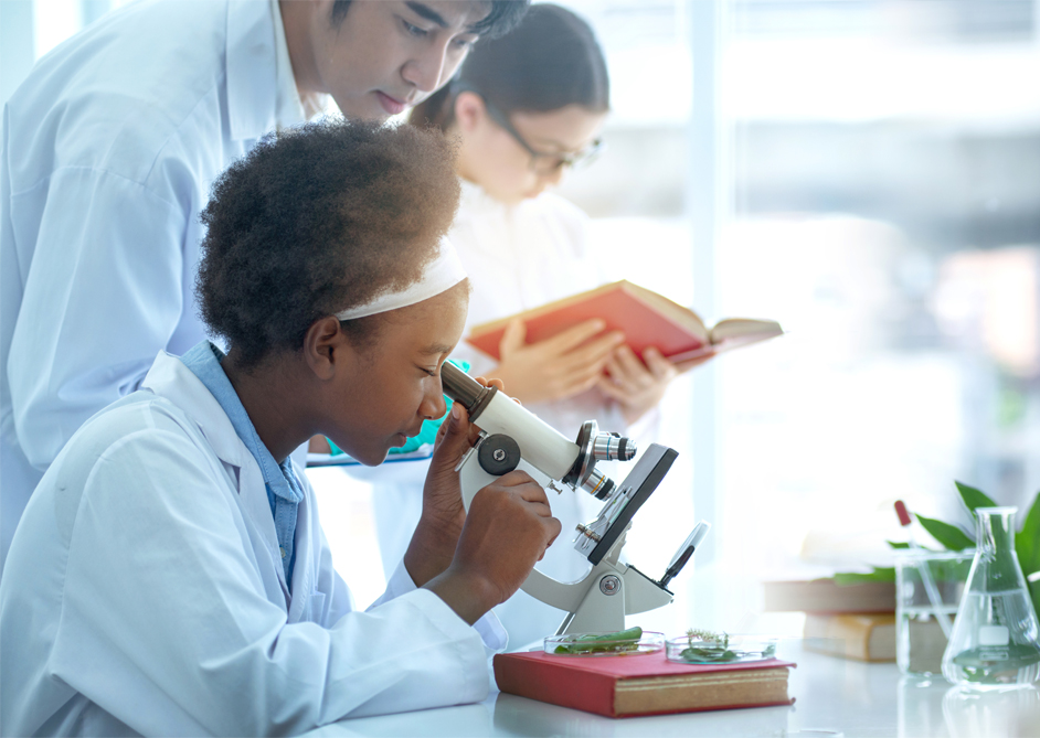 Image of students working in a science classroom with their teacher looking at slides in through microscope.